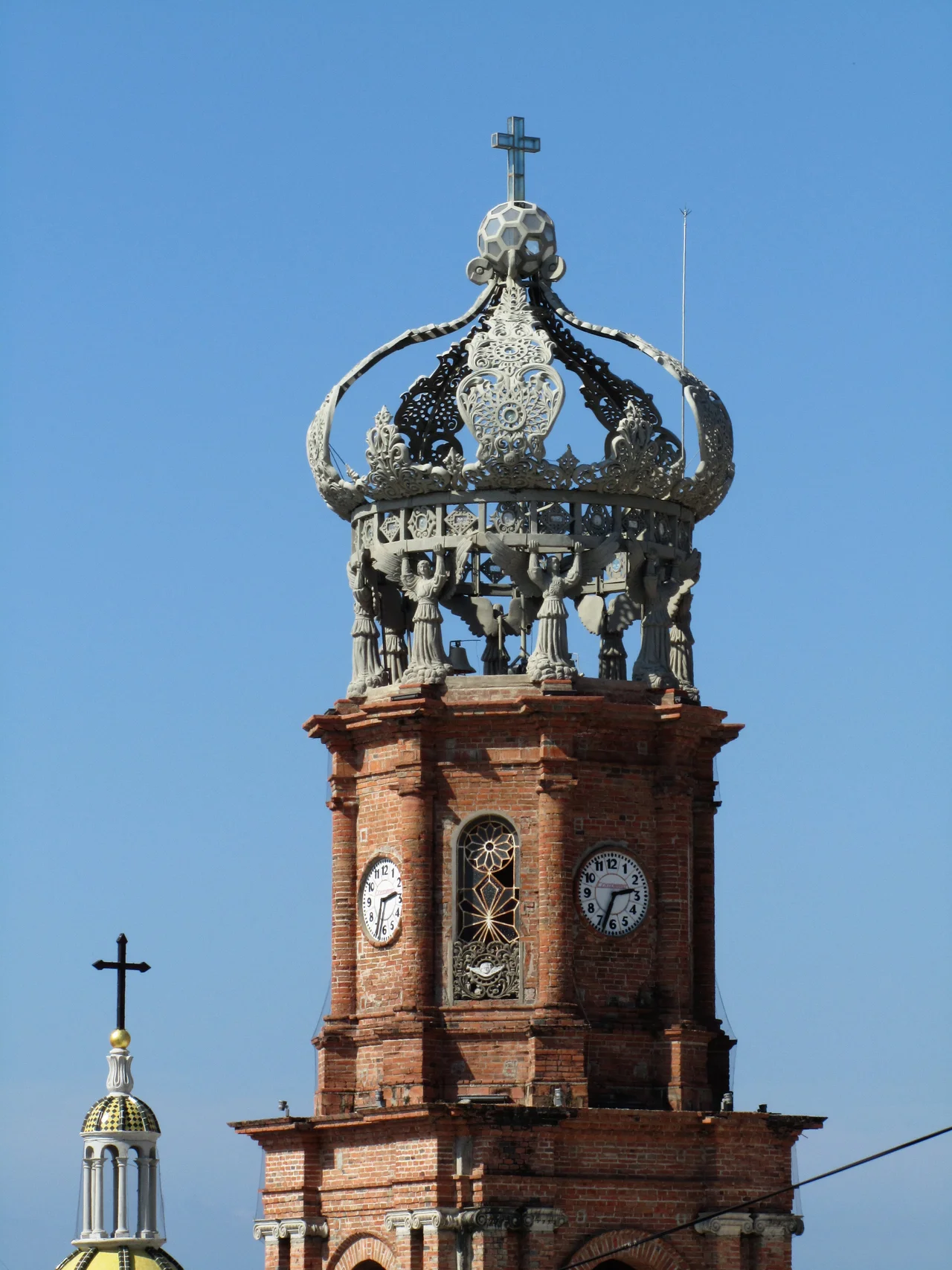 The Crown of Our Lady of Guadalupe Cathedral — Puerto Vallarta, Jalisco state, México.
Author: Sculptor and painter Carlos Terres.
10.00 m in diameter and 15.50 m in height; sculpture in terroca (terres stone).
The master sculptor and painter Carlos Terres made The Crown of Our Lady of Guadalupe basing his monumental sculpture in Nahuatl world Tecuntlanopeuh which means "that which has its origin at the peak of the boulders", alluding to the original name of the port, presently known as Puerto Vallarta.
Symbolic elements of the sculpture are as follows. Eight angles wearing Marian symbols on their breast are holding the crown. The gems of the ring represent the 24 hours of the day. The five small palms represent the joyful mysteries of the Marian rosary. The five large palms represent the founding of Puerto Vallarta on December 12, 1851.
Construction of the parish church began on April 15, 1883. The second phase of construction in 1915. The naming of the parish church in 1921. The borders of the sculpture are formed by a world of glass and a cross.
Benediction by Bishop P. Ricardo Waty on October 12, 2009.
Parish church of Our Lady of Guadalupe, Puerto Vallarta, Jal. Mexico.