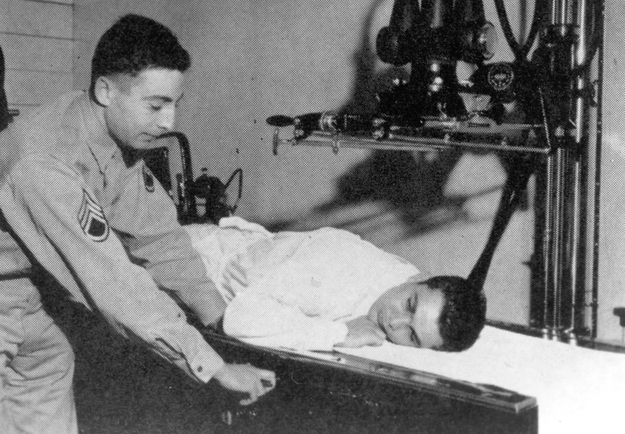 A U.S. Army Air Force X-ray technician with the rank of a Staff Sergeant, positions a patient for an X-ray at the 4167th Station Hospital at Fairfield-Suisun Army Air Field during WWII