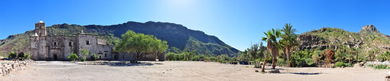 North side facade of Misión San Francisco Javier de Viggé-Biaundó.
The mission appears on the left amongst its oasis surroundings of palm trees and mountain ranges. 270° Panorama.
Photo by Gregg M. Erickson.