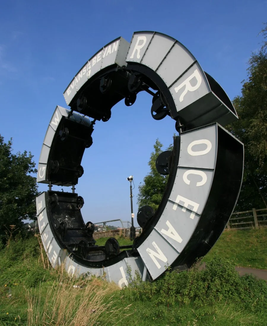 Wheel o Drams Sculpture at Maesycwmmer near Caerphilly. Unveiled in 2000 to commemorate area's industrial history. Sculptor was Andy Hazell.