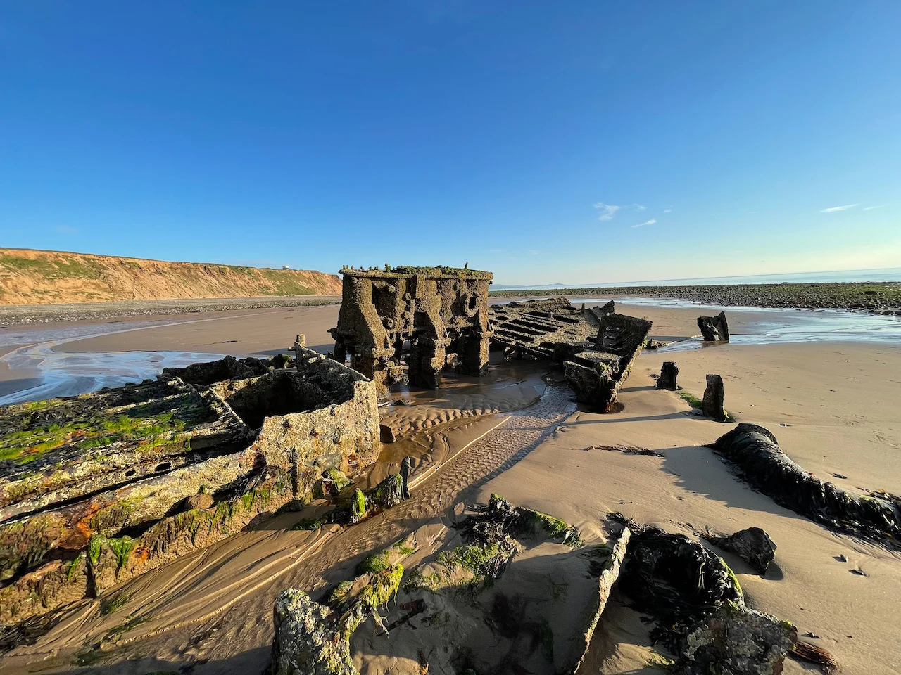 Close up view of stern section. From left to right: boiler, engine, stern. Background: cliffs of Jurby Head on the left, Peel Hill in the distance on the right.