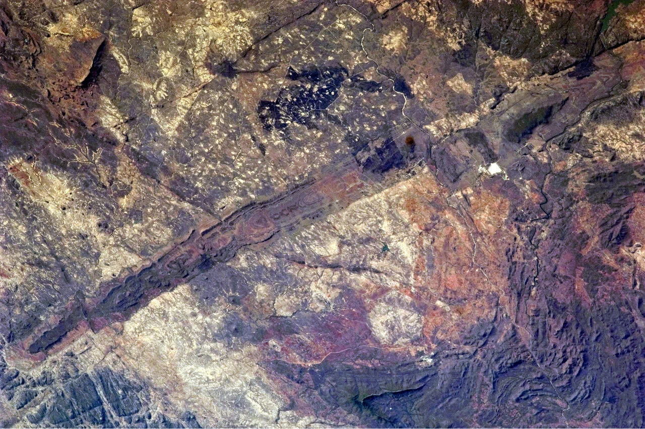 The Great Dyke of Zimbabwe. Although originally named as a dyke (The Great Dyke of Rhodesia) when first studied by geologists in the 19th century, it is now known to be a layered lopolith, not a dyke. The southern end of the dyke is captured in this photograph taken by astronauts. Two large burn scars from fires are visible at image top centre. North is to the right.