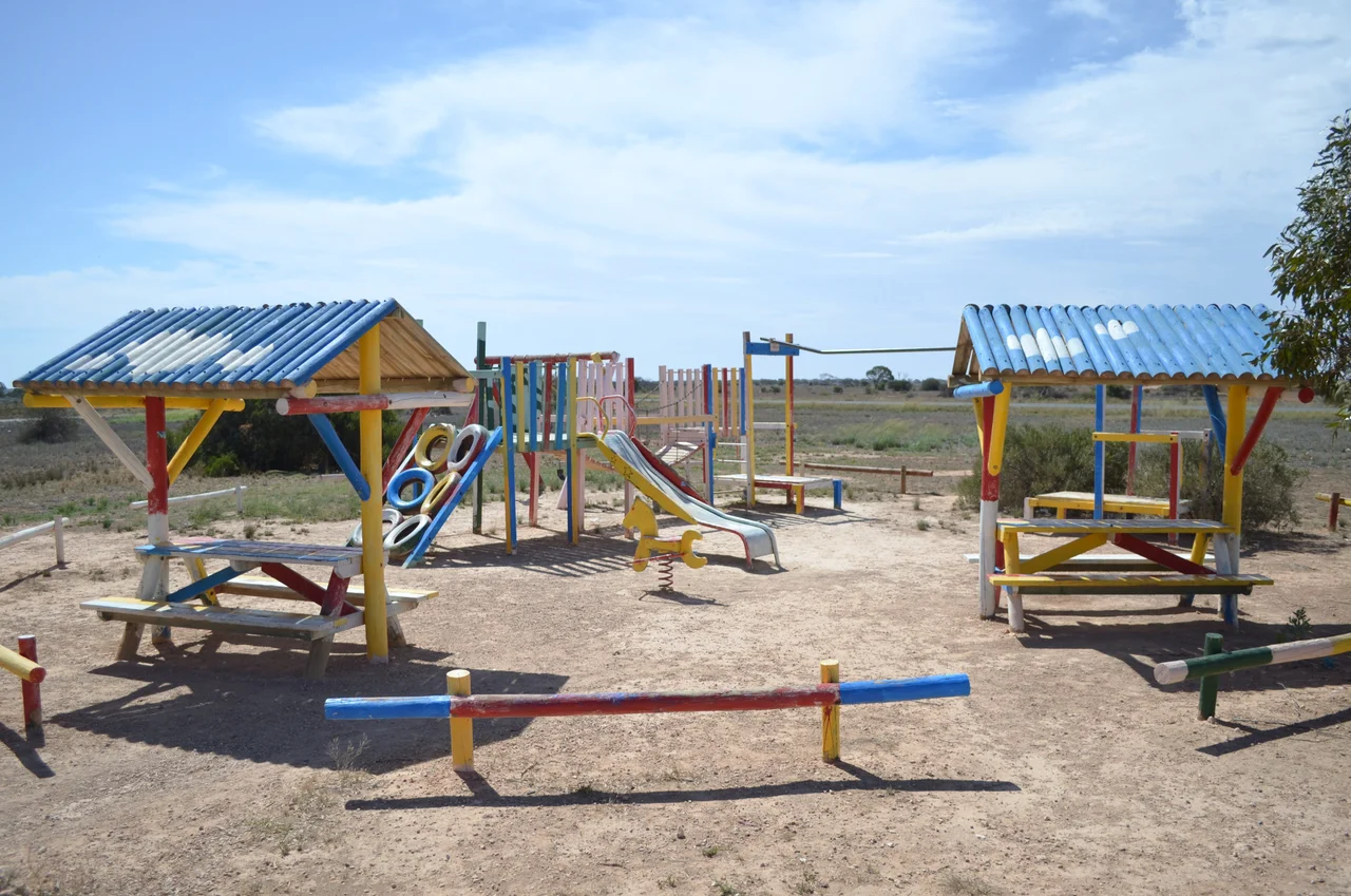 An old style playground, constructed of timber and steel, at the Cocklebiddy roadhouse, on the Nullarbor Plain, Western Australia. Photo taken from the forecourt of the roadhouse, looking towards the Eyre Highway, which is visible in the background.