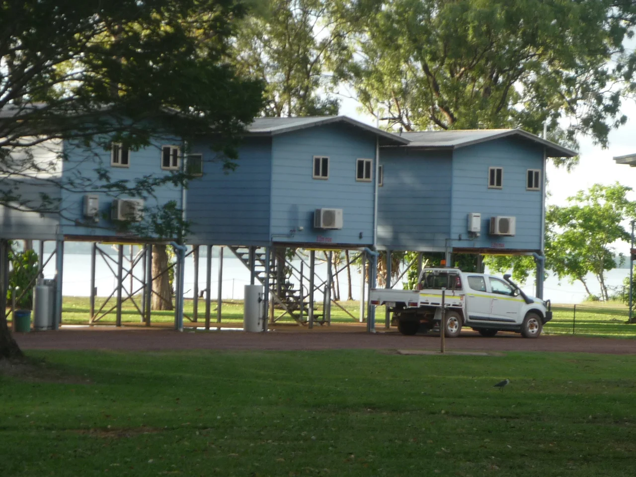 Weipa, far north Queensland, Australia. Shows three cabins raised above the ground and a mining company four-wheel drive utility motor vehicle. Cabins look towards the coastal Mission River.