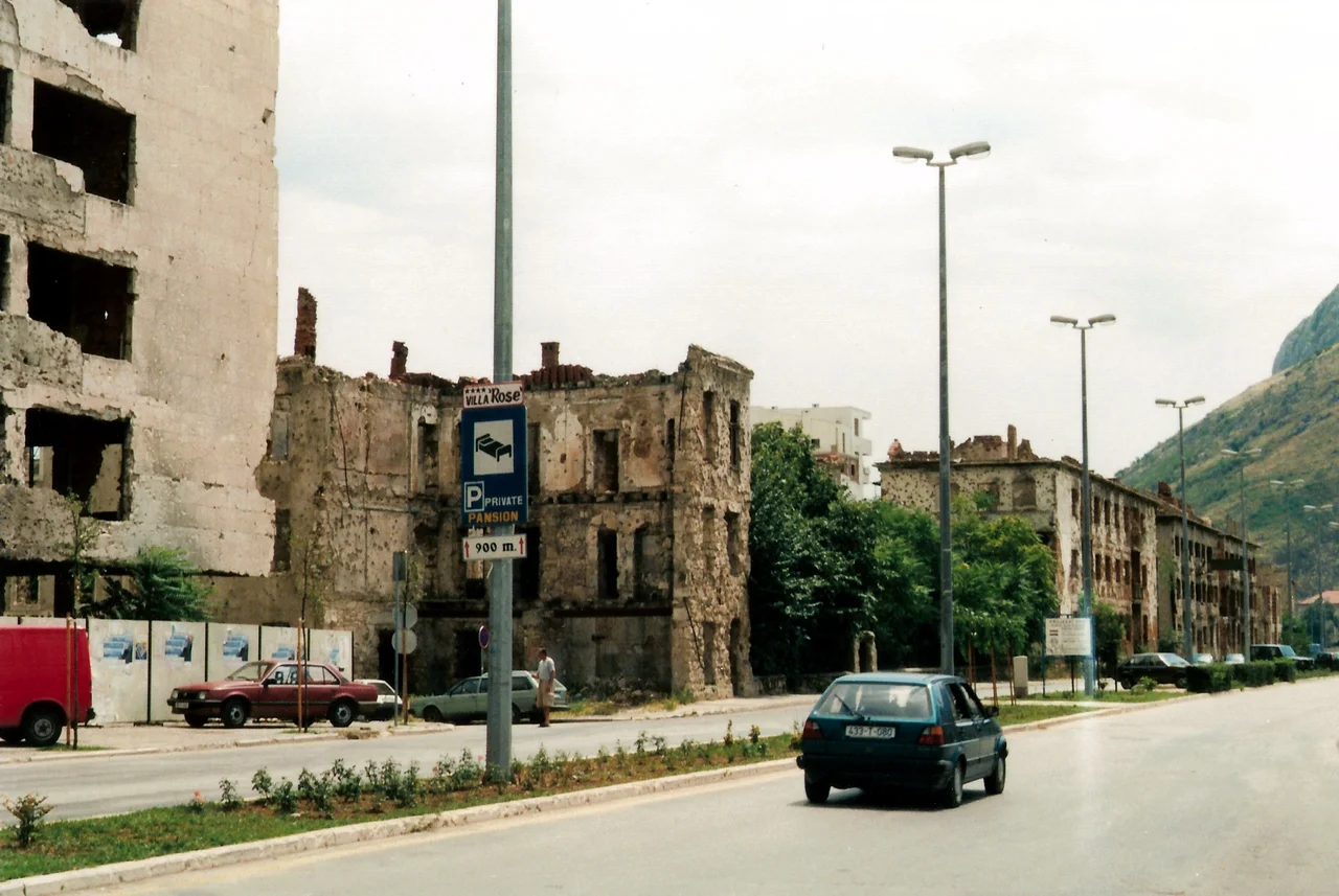 Damaged houses in Mostar (the west bank (Croat)) . Damage is from the Bosnian War. Geolocation is a guess.
Scan from a conventional photo. Enhanced with The Gimp.