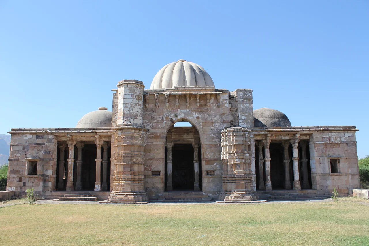 Champaner, Lila Gumbaj Ki Masjid
Champaner, also known as Muhammadabad, is a historical city in the state of Gujarat, in western India. The city was briefly the capital of Gujarat.
It was founded by Vanraj Chavda, the most prominent king of the Chavda Dynasty, in the 8th century. He named it after the name of his friend and general Champa, also known later as Champaraj. By the later 15th century, the Khichi Chauhan Rajputs held Pavagadh fort above the town of Champaner. The young Sultan of Gujarat, Mahmud Begada, deciding to attack Champaner, started towards it with his army on 4 December 1482. After defeating the Champaner army, Mahmud captured the town and besieged Pavagadh, the well-known hill-fortress, above Champaner, where king Jayasimha had taken refuge. He captured the Pavagadh fort on 21 November 1484, after a siege of 20 months. He then spent 23 years rebuilding and embellishing Champaner, which he renamed Muhammadabad, after which he moved the capital there from Ahmedabad. In 1535, after chasing away Bahadur Shah, Humayun personally led some 300 Mughals to scale the fort on spikes driven into rock and stonework in a remote and unguarded part of the citadel built over a precipitous hillside on Pavagadh Hill. Large heaps of gold, silver and jewels were the war booty even though Bahadur Shah had managed to escape to Diu. Champaner is today the site of the Champaner-Pavagadh Archaeological Park, which UNESCO designated a World Heritage Site in 2004.
There are eleven different types of buildings at the UNESCO-protected Champaner-Pavagadh Archaeological Park, including mosques, temples, granaries, tombs, wells, walls, and terraces. The monuments are situated at the foot of and around the Pavagadh Hill. The Baroda Heritage Trust lists 114 monuments in the area, of which only 39 are maintained by the Archeological Survey of India, due to limited funding.
Lila Gumbaj Ki Masjid, built on a high plinth, has a frontage with an arched entrance at the centre flanked by two lateral arches. Initially, three entrances existed on the east, south, and north directions. There are well spaced minarets fashioned with horizontal cornices and mouldings, and decorated niches. Of the three domes, the central one has a fluted design and is colourful. On the north-east corner there is a rectangular ablution tank with a deep drain in front. Inside the mosque, there are three mehrabs in the prayer hall and these are decorated with a central suspended kalash carved with floral motifs.
(source: en.wikipedia.org/wiki/Champaner, en.wikipedia.org/wiki/Monuments_of_Champaner-Pavagadh_Arc..., and en.wikipedia.org/wiki/Lila_Gumbaj_Ki_Masjid,_Champaner)