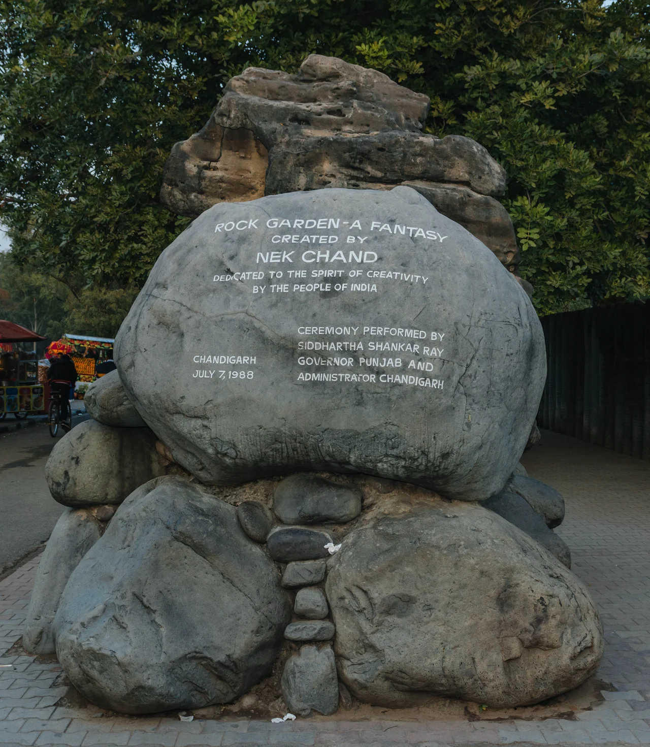 Rock Garden Memory Stone
Dedication day memorial - July 7, 1988
The Rock Garden of Chandigarh is a sculpture garden in Chandigarh, India. It is also known as Nek Chand's Rock Garden after its founder Nek Chand Saini, a government official who started the garden secretly in his spare time in 1957. Today it is spread over an area of 40 acres (161874.25 m²). It is completely built of industrial and home waste and thrown-away items.
It is near Sukhna Lake. It consists of man-made interlinked waterfalls and many other sculptures that have been made of scrap and other kinds of wastes (bottles, glasses, bangles, tiles, ceramic pots, sinks, electrical waste,brokenpipes, etc.) which are placed in walled paths.
