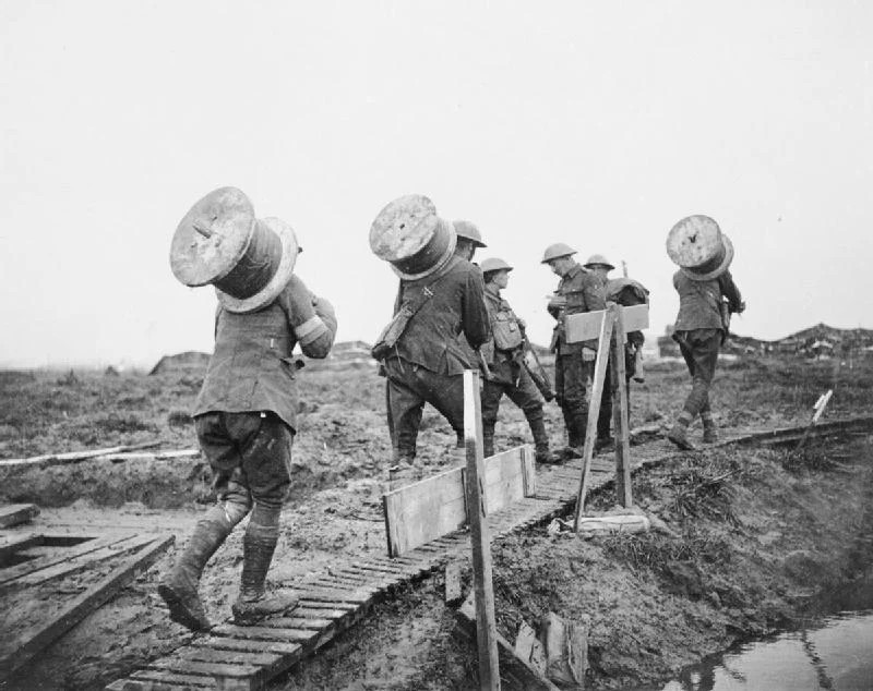 Battle of Poelcappelle 9 October 1917 : Royal Engineers taking drums of telephone wire along a duck board path up to the front between Pilckem and Langemarck.