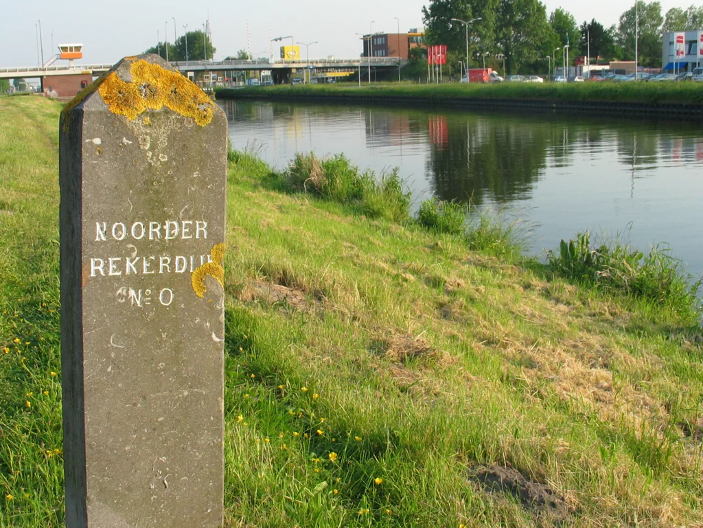 Markeringspaal aan de Rekerdijk, waar de dijk vanuit het noorden van het nl:Noordhollandsch Kanaal afbuigt naar het centrum van Alkmaar. De dijk volgt het tracé van het vroegere riviertje de Rekere. Op de achtergrond de Huiswaarderbrug, in de jaren '70 gebouwd tijdens de aanleg van de randweg om Alkmaar en de N245 naar Schagen
