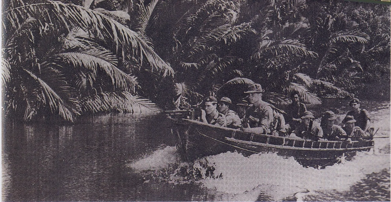 British Royal Marines Commando unit armed with machine gun and Sten gun patrolling using a boat in the river on Serudong, Sabah.